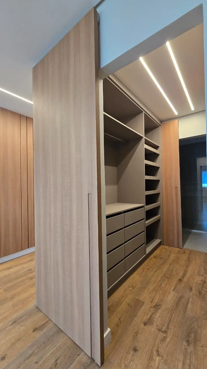 Closet com porta pivotante e iluminação linear no forro